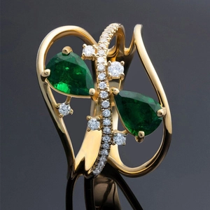 Primer plano de anillo cruzado con esmeraldas talla pera y pavé de diamantes