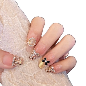 French style press-on nails with tweed patterns, pearls, and black bows on a nude base