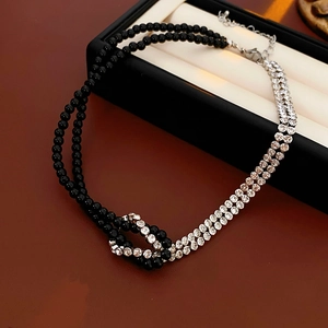 Detail of a double-layer necklace with black beads and silver rhinestone knotted chain