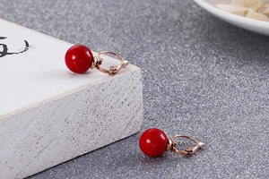 Gros plan détaillé des perles rondes rouges sur boucles d'oreilles en or rose chic