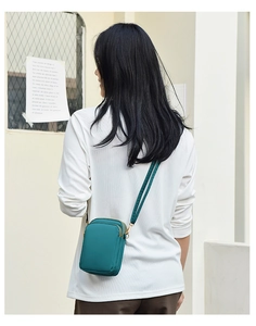 Close-up of peacock blue mini canvas crossbody phone bag with multi-layer zipper design