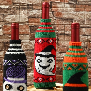 Three Halloween knitted wine bottle covers featuring pumpkin, ghost, and witch designs