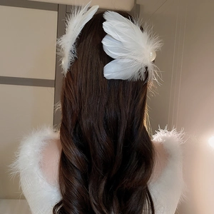 Detail showing a pair of elegant white feather hair clips with pearls on wavy hair