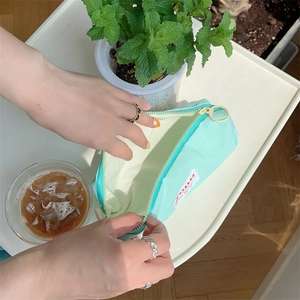 Top view of hands opening a mint green fabric pencil case in a cozy lifestyle setting