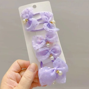 Detail of five purple polka dot mesh bow hair ties with pearl charms on card