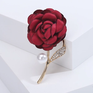 Detail of a dark red fabric rose brooch with golden leaves, rhinestones and a white pearl