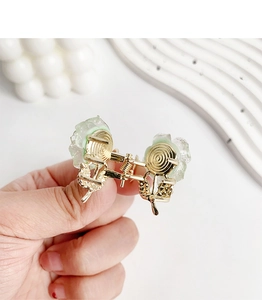 Close-up of light green flower hair claw clip with golden glitter and resin petals