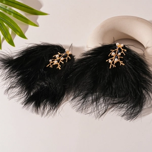 Détail de boucles d'oreilles ethniques avec plumes noires, branches dorées et perles