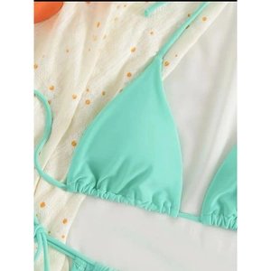Close-up of mint green triangle bikini top with drawstring details on daisy fabric background
