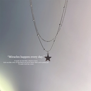 Detail of silver double-layered star necklace featuring beads and star pendant