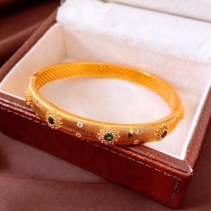 Détail d'un bracelet vintage plaqué or 24 carats avec émeraude verte et oxydes de zirconium
