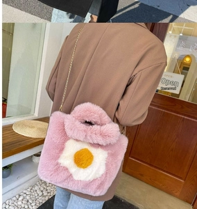 Detail of pink faux fur tote bag with fried egg patch and gold metal chain strap