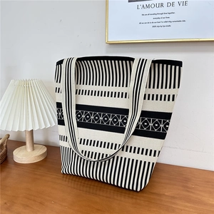 Detail of black and white striped knit tote bag texture on dark wood background