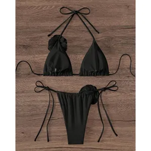 Two-piece black bikini set with 3D floral accents on wooden texture background