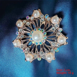 Macro detail of camellia brooch with cream pearl and rhinestones in rose gold
