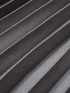 Macro shot of dark grey accordion pleated fabric texture with fine matte finish details