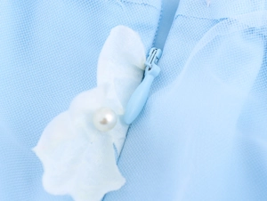 Detail of invisible zipper with white 3D flower and pearl on light blue mesh dress
