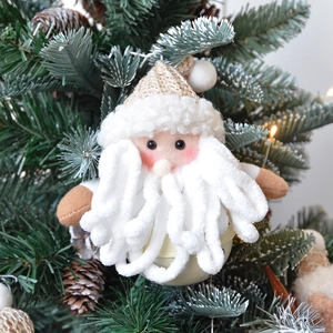 Detail view of plush Santa Claus hanging ornament with bell on a Christmas tree branch