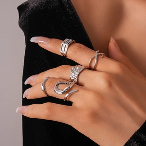 Close-up of five minimalist silver geometric rings worn by a model in a luxury style