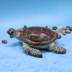 Realistic resin sea turtle figurine on blue decorative sand with pebble accents