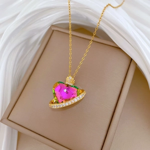 Close-up of golden crown heart pendant with colorful crystals on a white silk background