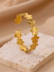 Détail du bracelet fleur en acier plaqué or 18 carats avec finition en métal brossé