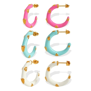 Three pairs of colorful C-shaped enamel earrings with gold heart relief in pink, blue, and white