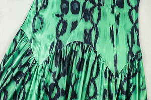 Detailed view of the pleated satin fabric with green print and smooth silk texture