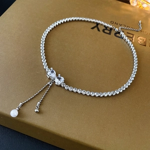 Detail of silver bow choker with zircon heart, pearl tassels and elegant layered chains