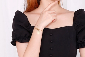 Detail of a vintage gold-plated bracelet with an engraved rectangular star and moon charm