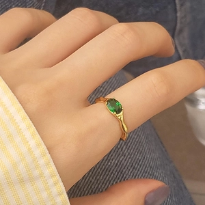 Detail of vintage gold ring with oval green zircon and irregular lava texture on hand