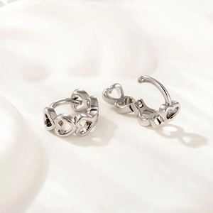 Elegant hollow heart-shaped silver earrings on soft white fabric background