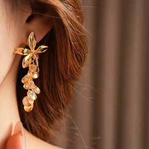 Close-up of vintage flower earrings with amber crystal tassels worn by a model
