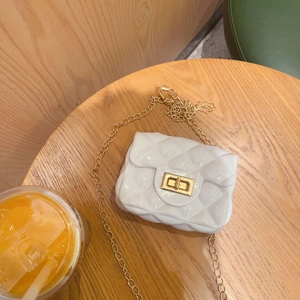 Detalle del mini bolso acolchado blanco con cadena dorada y cierre sobre mesa de madera