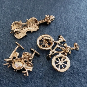 Three-piece gold alloy pin set with violin, bicycle and drum shapes on blue texture