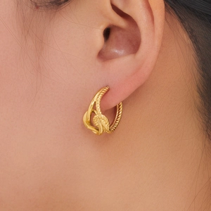 Close-up of golden stainless steel twisted knot earring worn on earlobe for small size reference