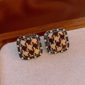 Detail of square houndstooth earrings with sparkling rhinestones and metal border