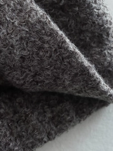 Detailed macro view of high-density dark grey faux shearling fabric for casual jackets