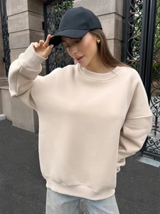 Outdoor shot of an oversized beige crewneck sweatshirt with dropped shoulders and ribbed cuffs