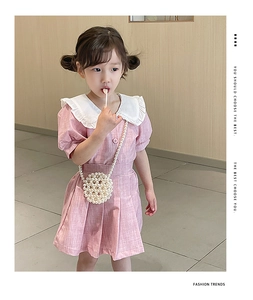 Close-up of a pink girl's dress with white doll collar and pearl woven crossbody bag