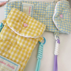 Detail of quilted camera pouch with heart patterns, colorful lanyards, and soft cotton texture