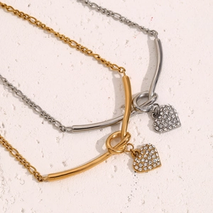 Détail de chaînes Figaro en or 18 carats et argent avec nœud en V et pendentifs cœur cristal