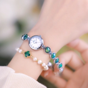 Close-up of elegant women's watch featuring malachite green inserts and pearl bracelet set