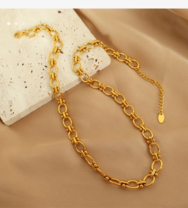 Detail of a golden titanium steel beaded chain necklace on elegant silk background