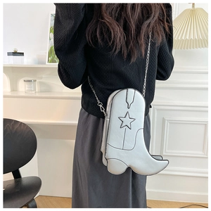 Silver metallic boot-shaped crossbody bag with star pattern and chain strap on model