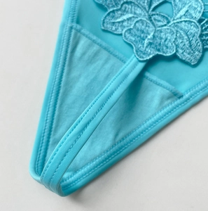Detailed close-up of blue lace embroidery and elastic fabric texture on women's thong underwear