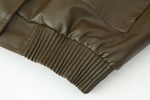 Close-up of the elastic ribbed hem and detailed grain on a dark brown faux leather jacket