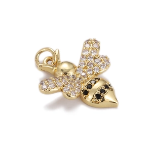 Macro view of a gold bee pendant with white zircons and black gemstone wings detail