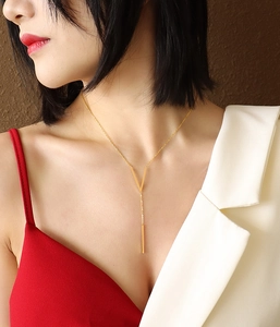 Close-up of minimalist gold V-bar necklace on model showing its sleek geometric design