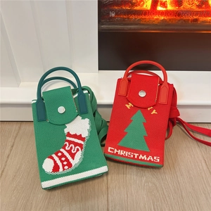 Red and green Christmas knitted phone bags with festive patterns on warm wooden floor
